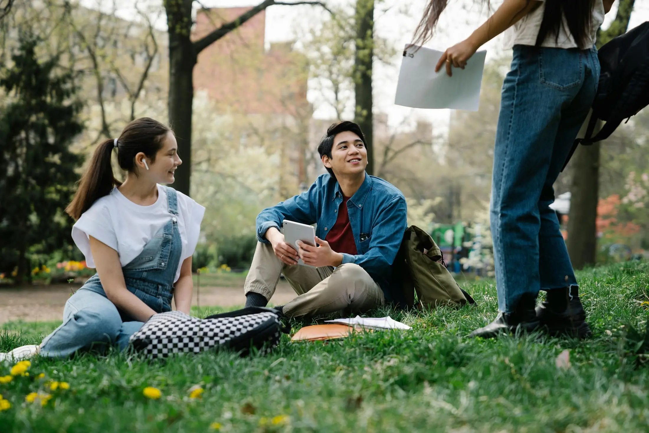 Students sitting together in a park with a tablet